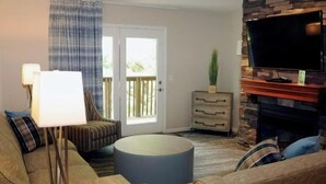 A living room with a sofa, a coffee table, a lamp, a TV, and a fireplace. - Cozy 1-bedroom resort with AC in welcoming Massanutten with waterPark access (Massanutten)