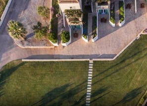 An aerial view of a property with a paved driveway, a lawn, and a building with multiple windows and a door. - Sea Front Villa Elunara, Divine Sea Views, Private furnished Terrace, Shared. (Neapoli)