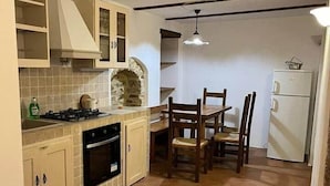Una cocina con una mesa de comedor y sillas, un refrigerador y una estufa.
