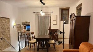 Una sala de estar con una mesa de comedor, un sofá, una lámpara y un televisor.