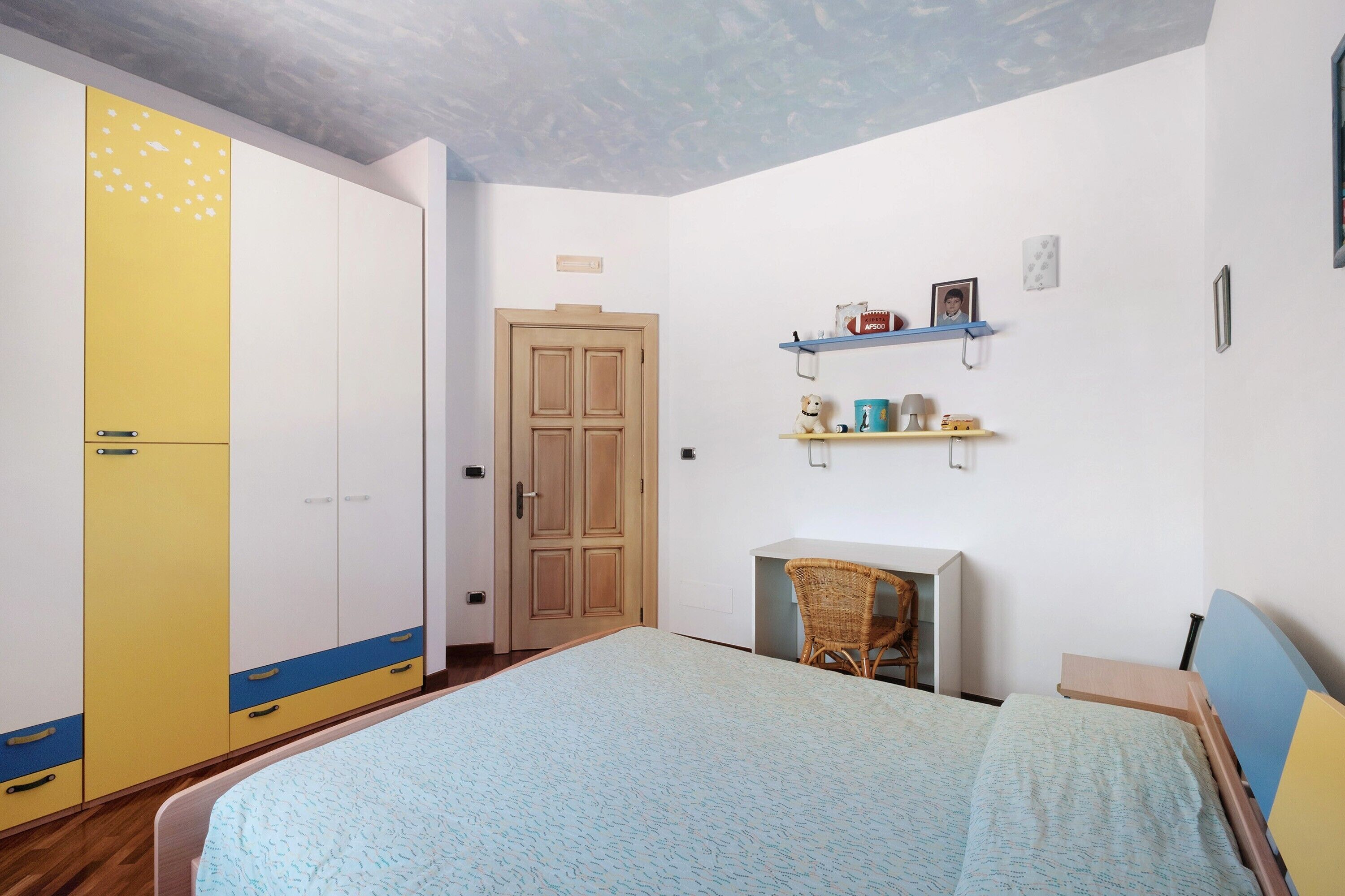 Une chambre à coucher comprenant un lit, une armoire, un bureau et des étagères.