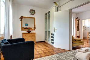 A room with a sofa, a wooden dresser, a mirror, a cabinet with glass doors, and a patterned rug. - Talamone Apartment View by Mamo Florence (Talamone)