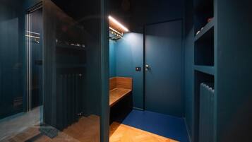 Ein Zimmer mit blauer Wand, einer hölzernen Bank, einem Heizkörper und einer Tür mit Griff.
