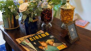 Una mesa con un cartel de cine antiguo, un código QR enmarcado y jarrones decorativos con flores y hierbas secas.