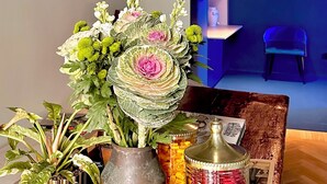 A room with a chandelier, a table with a vase of flowers, a bottle, and a picture frame. - Fontana 16 Rooms (Milan)
