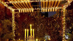 An outdoor dining area with a table set for a meal, surrounded by candles and string lights. - Fontana 16 Rooms (Milan)