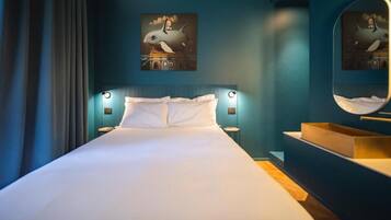 Una moderna camera d'albergo con un letto grande, un comodino, uno specchio e opere d'arte alle pareti.