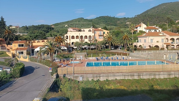 A coastal resort with a swimming pool, villas, and a view of the sea. - Stella Marina: Three-Bedroom Apartment with Pool, 3 Balconies, and Free Parking (Pietra Ligure)