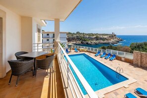 Un balcón con piscina, sillas y una mesa.