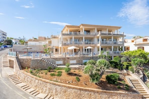 A multi-story hotel with balconies, a swimming pool, and a landscaped garden. - Apartment 'Aptos Villa Sirena Vista Mar' with Shared Pool, Wi-Fi and Air Conditioning (Cala Figuera)