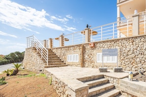 Ein Steinhaus mit einer Treppe, die zu einem Balkon führt, einem Schild, das einen privaten Pool kennzeichnet, und einem klaren Himmel.