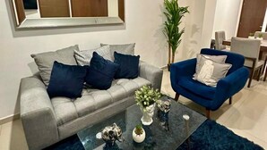Een moderne woonkamer met een grijze bank, een blauwe fauteuil en een zwarte salontafel.