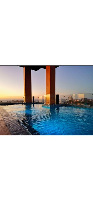 Une piscine à l’eau d’un bleu cristallin, entourée d’une terrasse carrelée.