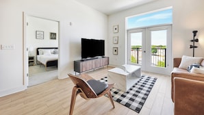 Un salon moderne doté d’un téléviseur à écran plat, d’un canapé, d’une table basse et d’un balcon offrant une vue agréable.