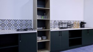 Μια κουζίνα με γκαζιέρα, ράφια και πλακάκια στον τοίχο πάνω από τον πάγκο.