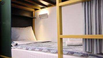 A bunk bed with a headboard, a wall-mounted light, and a curtain.