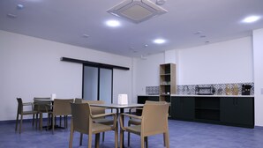 Μια σύγχρονη κουζίνα με τραπεζαρία, που περιλαμβάνει ένα τραπέζι με καρέκλες, έναν πάγκο κουζίνας με ράφια και έναν πλακιδωτό τοίχο πίσω από τον πάγκο.