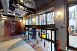 A modern bar area with a wooden counter, metal chairs, and a fire extinguisher.