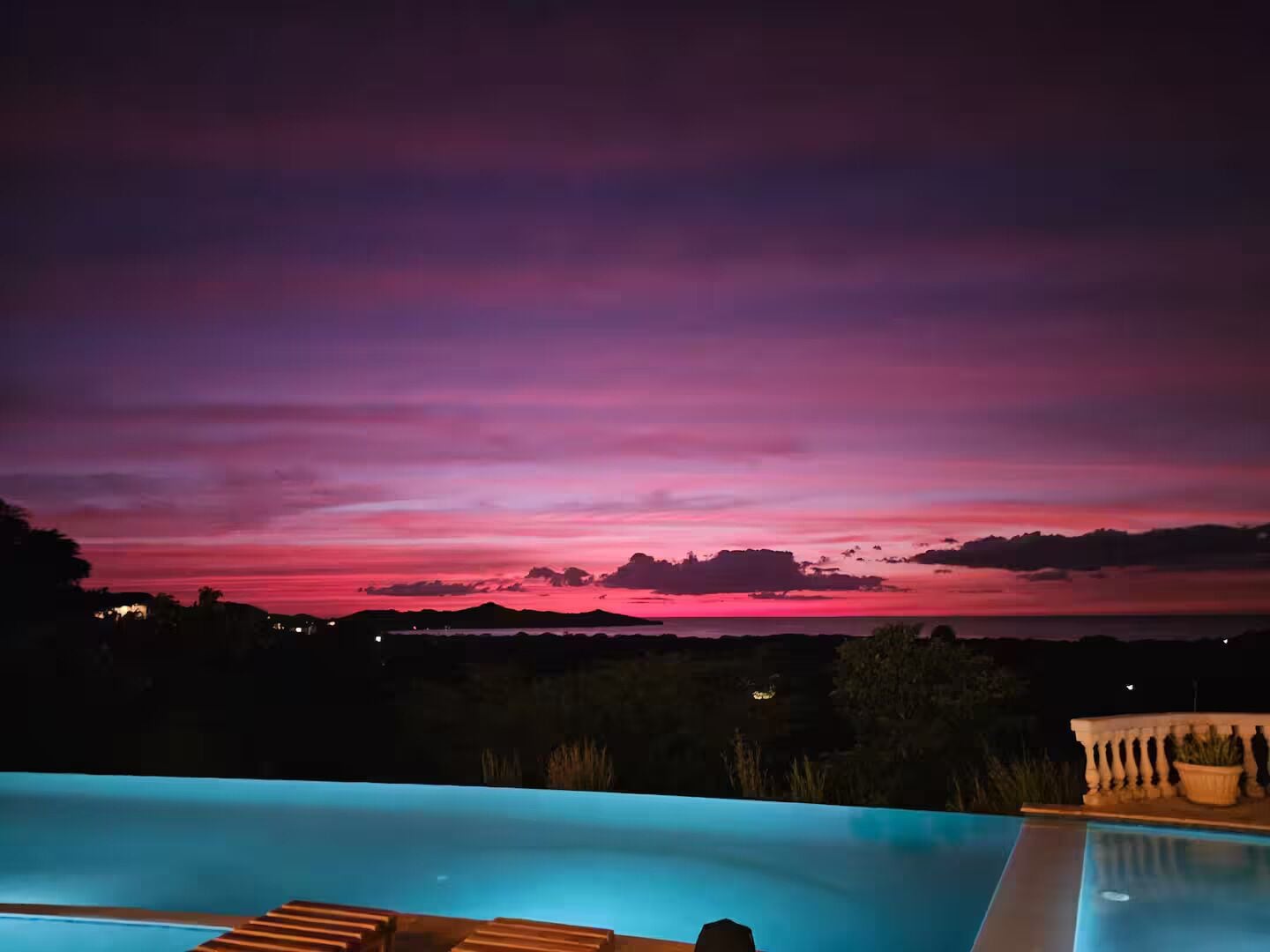 Ein Pool mit Blick auf einen Sonnenuntergang über einer Landschaft.