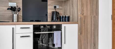 A kitchen with a built-in oven, a coffee maker, and a kettle.