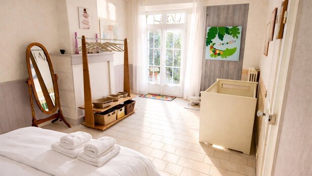 Una camera da letto con un letto, una cassettiera in legno, uno specchio e una finestra vista verde.