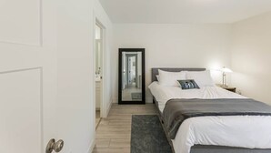 Ein Schlafzimmer mit Bett, Nachttisch, Lampe und Spiegel.