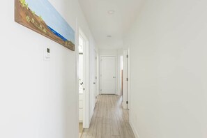 A hallway with a wooden floor, white walls, and a door at the end. - Red Sand Roost - Stratford Duplex Minutes from Beach and Charlottetown (Stratford)