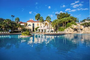A hotel with a large pool, palm trees, and a building with a red roof. - Cozy 2-bedroom hotel villa ona resort in southwest Orlando (Orlando)