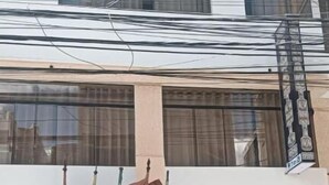 A building with a ground-floor entrance, a balcony with railings, and a sign above the entrance. - HOTEL SAN ANTONIO  (Puno)