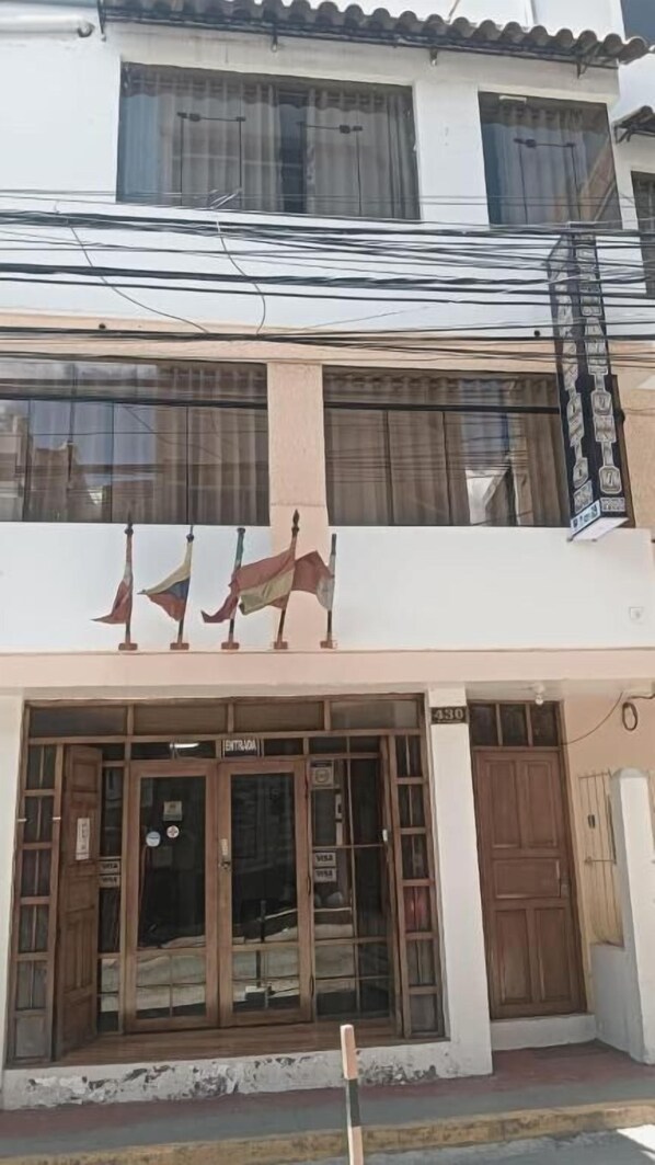 A building with a ground-floor entrance, a balcony with railings, and a sign above the entrance. - HOTEL SAN ANTONIO (Puno)