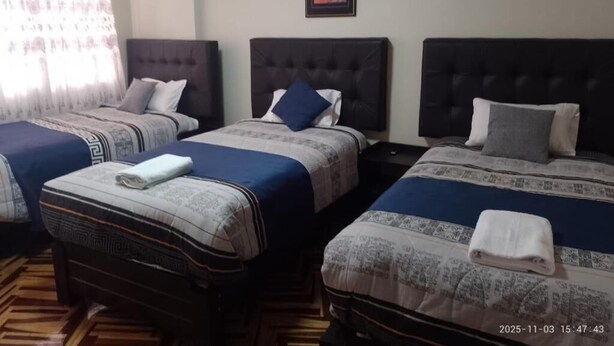 A hotel room with three beds, each with a headboard and pillows, and a wooden floor. - HOTEL SAN ANTONIO  (Puno)