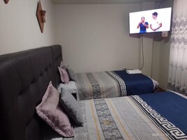 Un dormitorio con dos camas, un televisor montado en la pared y un adorno decorativo en la pared.