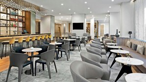 A modern hotel lobby with a bar area, seating arrangements, and a large TV screen. - Ac Hotels By Marriott Boise Downtown (Boise)