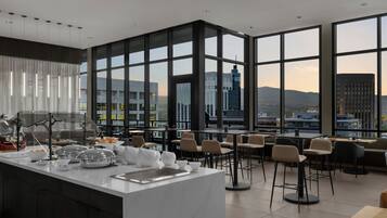 A modern dining area with a large window view, a central island with kitchen appliances, and multiple seating options.