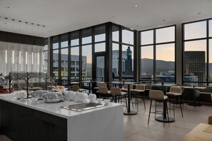 Ein zeitgemäßer Essbereich mit großem Fensterblick, einer zentralen Kochinsel mit Küchengeräten und verschiedenen Sitzgelegenheiten.