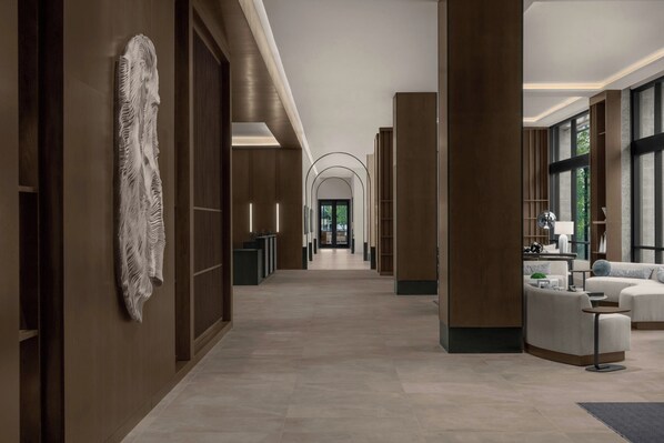 A modern hotel corridor with a central hallway, wooden paneling, and a reception area with seating. - Ac Hotels By Marriott Boise Downtown (Boise)
