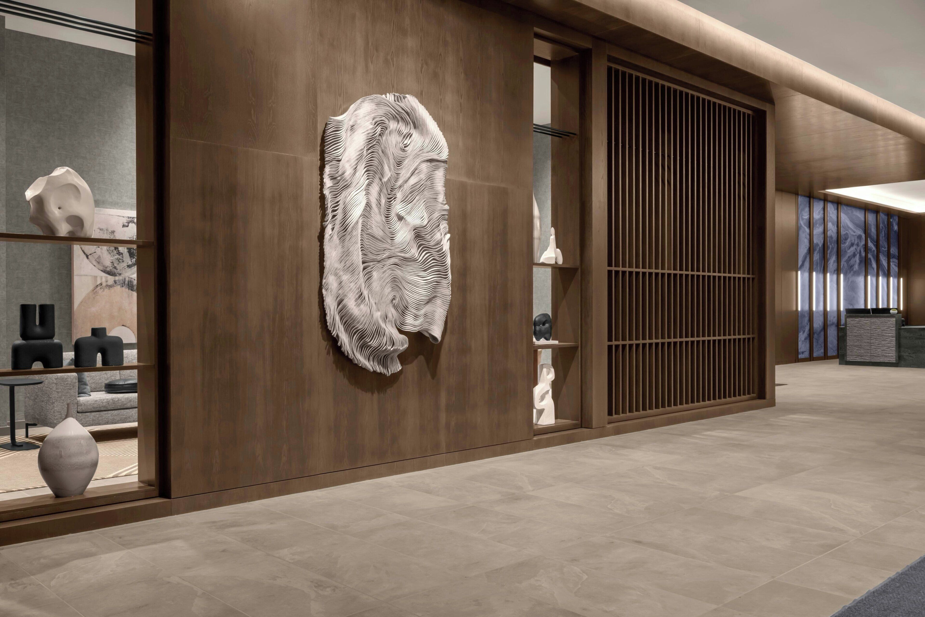 A modern interior with a wooden wall, a large abstract sculpture, and a reception desk.