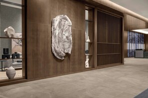 Een modern interieur met een houten wand, een groot abstracte sculptuur en een receptiebalie.