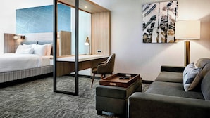 Ein Hotelzimmer mit Bett, Schreibtisch, Sofa und einem Gemälde an der Wand.