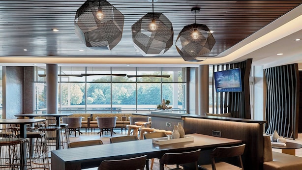 Ein modernes Restaurant mit großem Essbereich, mehreren Tischen und Stühlen, einem Fernseher und Blick ins Freie.