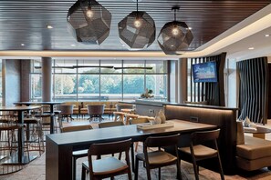 Un restaurant moderne doté d’une grande salle à manger, de nombreuses tables et chaises, d’un écran de télévision et offrant une vue sur l’extérieur.
