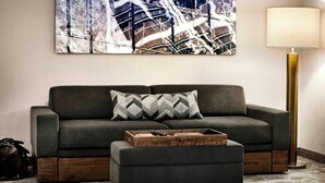 Ein modernes Wohnzimmer mit einer Couch, einem Hocker und einem Couchtisch aus Holz.