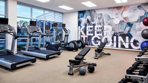 Ein Fitnessstudio mit Laufbändern, Crosstrainern und Gewichten.