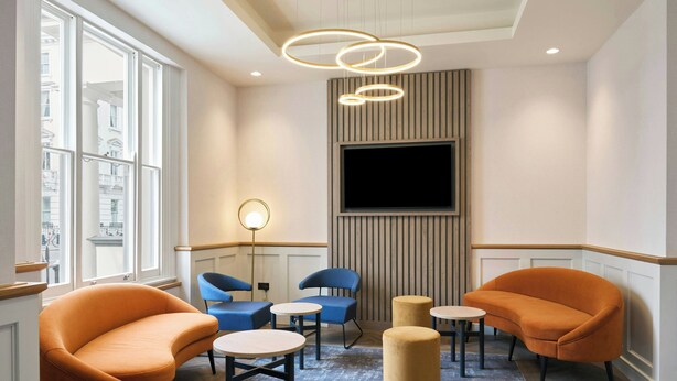 Un salon moderne doté d’un grand téléviseur, de sièges confortables et offrant une vue sur la ville.