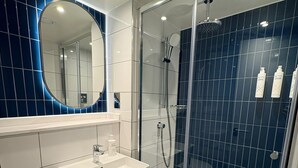 Une salle de bain moderne avec un lavabo blanc, un miroir et une douche.