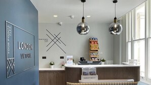 Un comptoir d’accueil avec une enseigne « MARRIOTT BONVOY », un mur bleu orné de l’inscription « LONDON VICTORIA » et un parquet en bois à motifs chevrons.