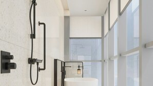 Une salle de bain moderne avec une baignoire sur pieds, une douche et une grande fenêtre qui laisse entrer la lumière naturelle.