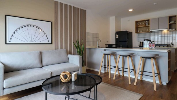 A modern living room with a sofa, a coffee table, and a kitchen area with stools. - w* | Modern & Cozy 2BR w/ Balcony in Miraflores (Miraflores)