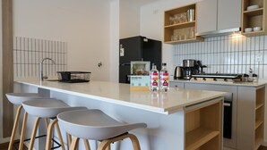 A modern kitchen with a central island, bar stools, a black refrigerator, and a stove. - w* | Modern & Cozy 2BR w/ Balcony in Miraflores (Miraflores)