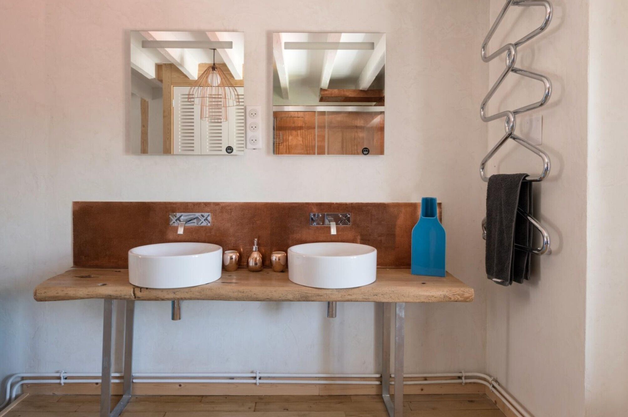 Un baño con dos lavamanos, un espejo y un perchero para toallas.